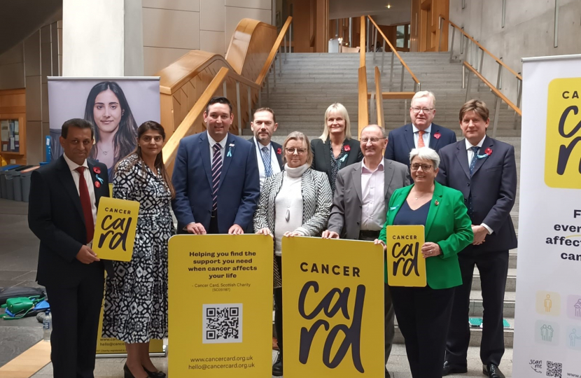 Alex and others from Holyrood posing on a staircase with Cancer Card signage.
