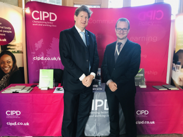 Alex and Marek standing in front of the CIPD booth at Holyrood.